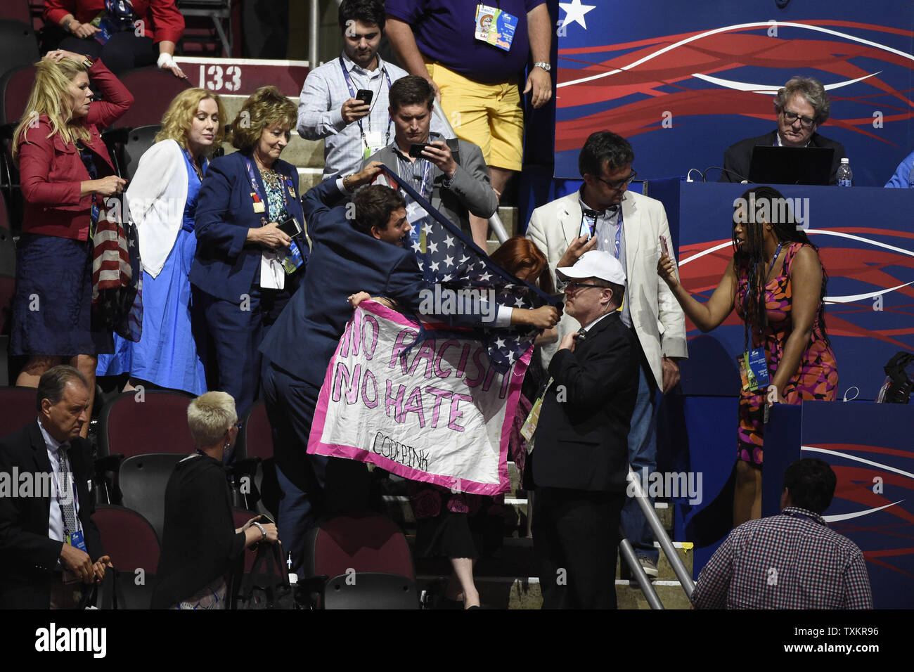 I repubblicani tentano di utilizzare bandierine americane a coprire fino a un codice rosa protester tenta di interrompere il procedimento della seconda giornata della Convention Nazionale Repubblicana a dall'Arena Quicken Loans in Cleveland Ohio sulla luglio 19, 2016. Donald Trump accetterà la nomina del Partito Repubblicano per Presidente il giovedì notte Luglio 21st. Foto di Pete Marovich/UPI Foto Stock