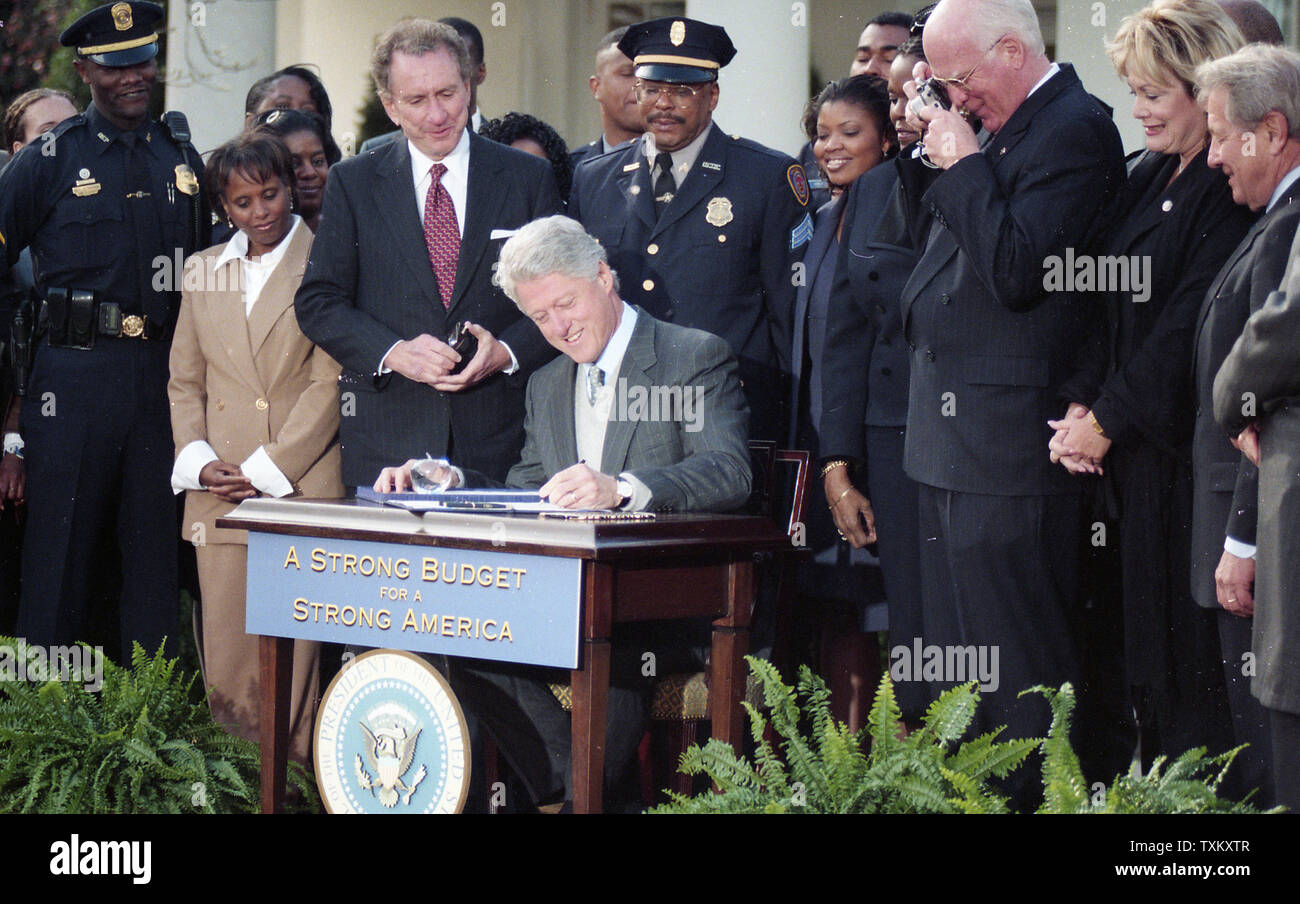 Stati Uniti Il presidente Bill Clinton firma il bilancio 2000, come il Sen. Arlen spettro (R-PA) (3 L) e Sen. Patrick Leahy (D-VT) (terza R) a guardare, alla Casa Bianca a Washington il 29 novembre 1999. UPI Foto Stock