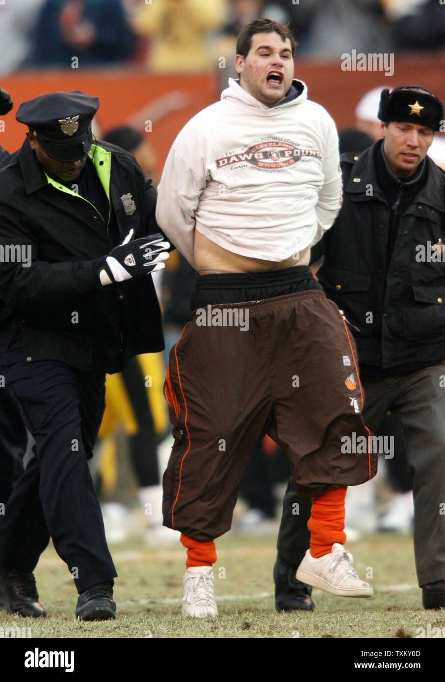 A Cleveland Browns ventola è scortato dal campo dopo egli lept dalle gabbie e corse attraverso il campo nel quarto trimestre del Cleveland Browns contro Pittsburgh Steelers gioco di calcio 24 dicembre 2005 al Cleveland Browns Stadium. Lo Steelers ha sconfitto il Browns 41-0. (UPI foto/Scott R. Galvin) Foto Stock