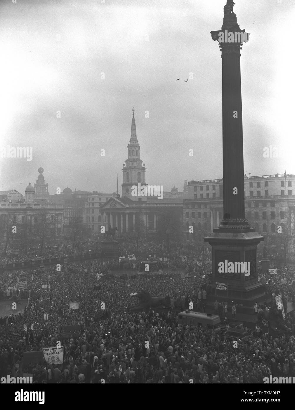 Imbevuto di pioggia ma in alta spiriti, alcuni dei 23.000 manifestanti che hanno partecipato alla santa Messa divieto-la-bomba rally all'ombra della Colonna di Nelson, a Trafalgar Square a Londra. Foto Stock