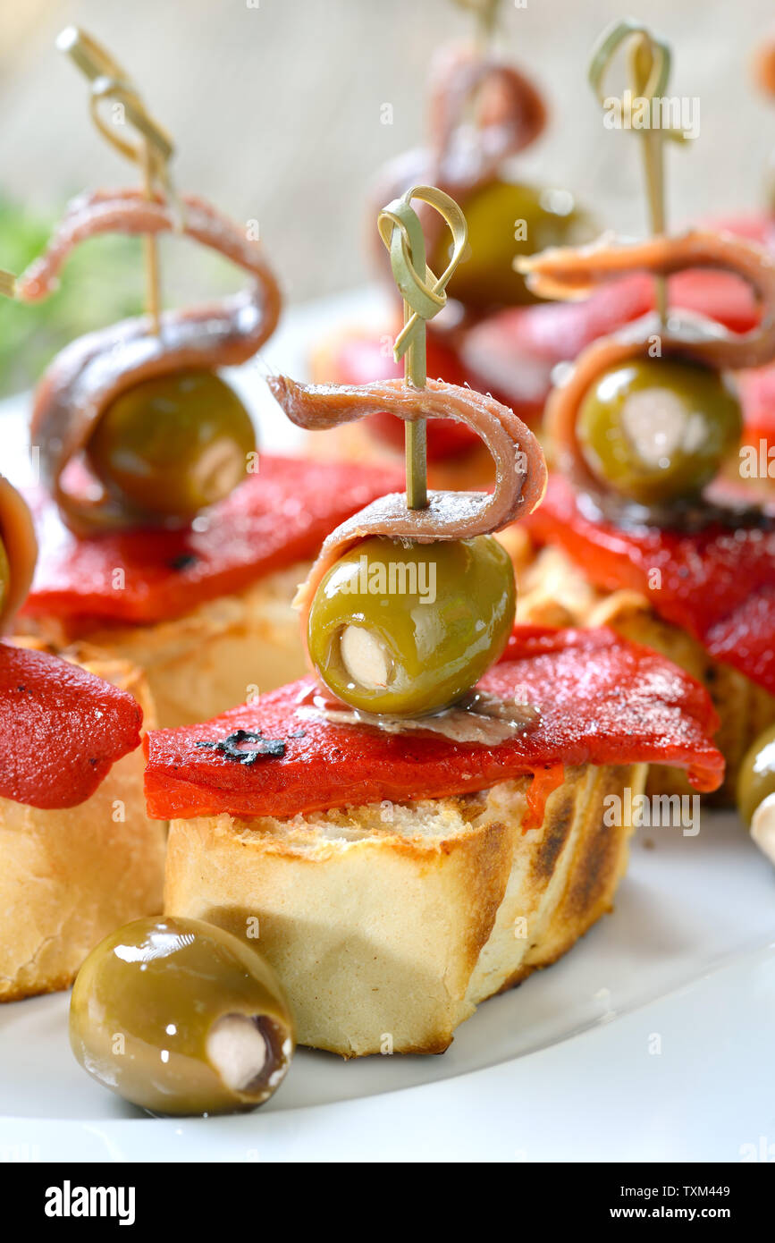 Lo spagnolo pinchos: Spiedini spuntini fatti di pane grigliato con arrosti e i peperoncini sott'aceto, olive ripiene e e sopra i filetti di acciuga Foto Stock