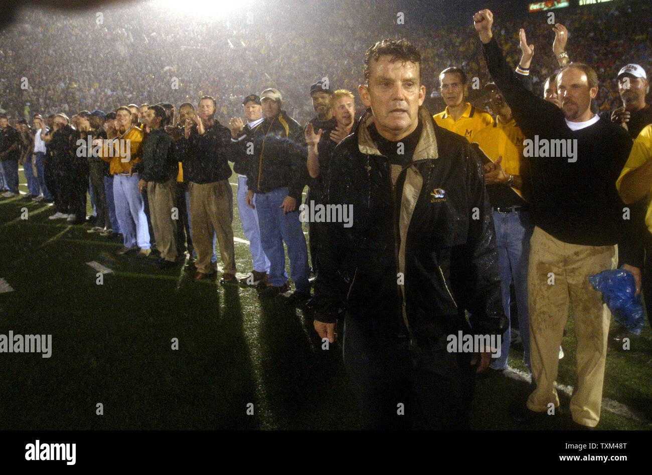 Imbevuto di pioggia ex University of Missouri head coach Warren poteri, stand con molti dei suoi ex giocatori durante un intermezzo del Missouri-Nebraska foortball partita al campo Faurot in Columbia, Mo su ottobre 11, 2003. Poteri e il suo ex giocatori da 1978- 1984, celebrata in un acquazzone tra quartieri, i venticinque anniversario dell'ultimo Missouri vincere contro Nebraska. Missouri beat Nebraska, 41-24. (UPI/BILL GREENBLATT) Foto Stock