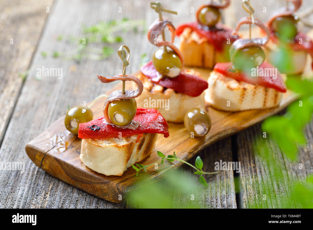 Lo spagnolo pinchos: Spiedini spuntini fatti di pane grigliato con arrosti e i peperoncini sott'aceto, olive ripiene e sopra i filetti di acciuga Foto Stock