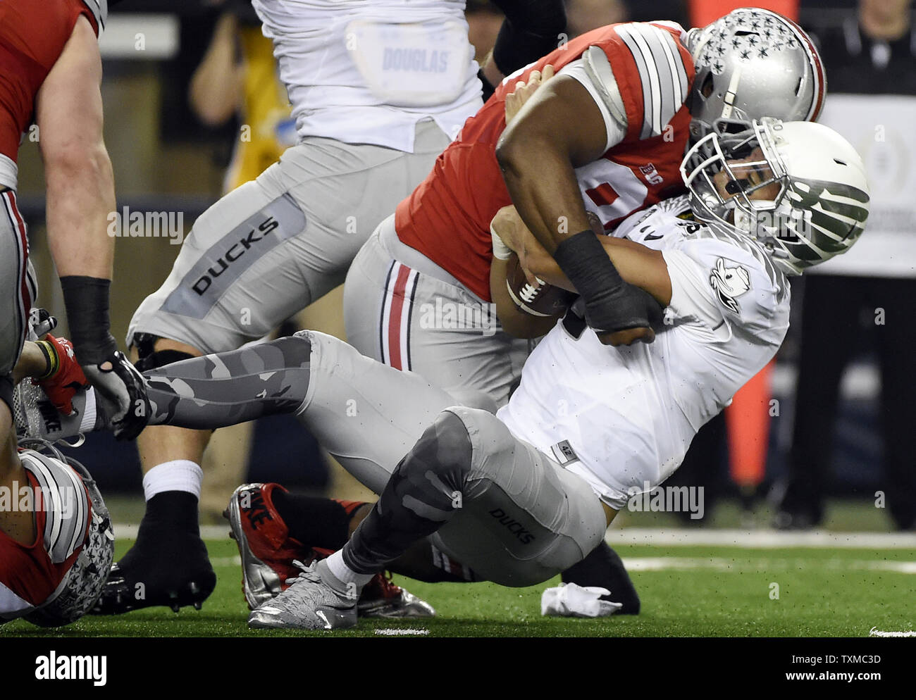 Oregon Ducks quarterback Marcus Mariota è saccheggiato da Ohio State Buckeyes Adolphus Washington per un cantiere 5 perdita nel primo semestre presso il College Football Playoff Campionato Nazionale di Arlington, Texas, il 12 gennaio 2015. Foto di Kevin Dietsch/UPI Foto Stock