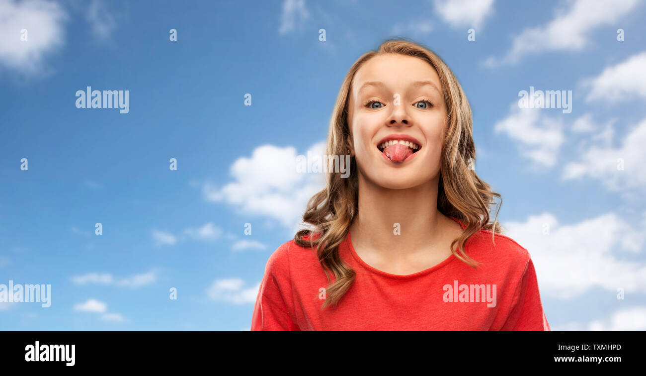 Ragazza adolescente in t-shirt rossa mostra la linguetta su sky Foto Stock