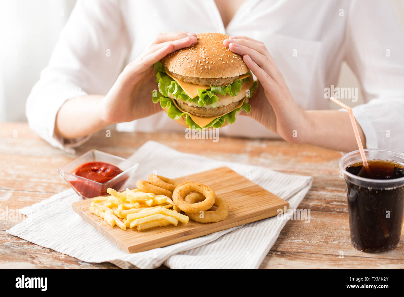 Close up della donna mangiare hamburger al ristorante Foto Stock