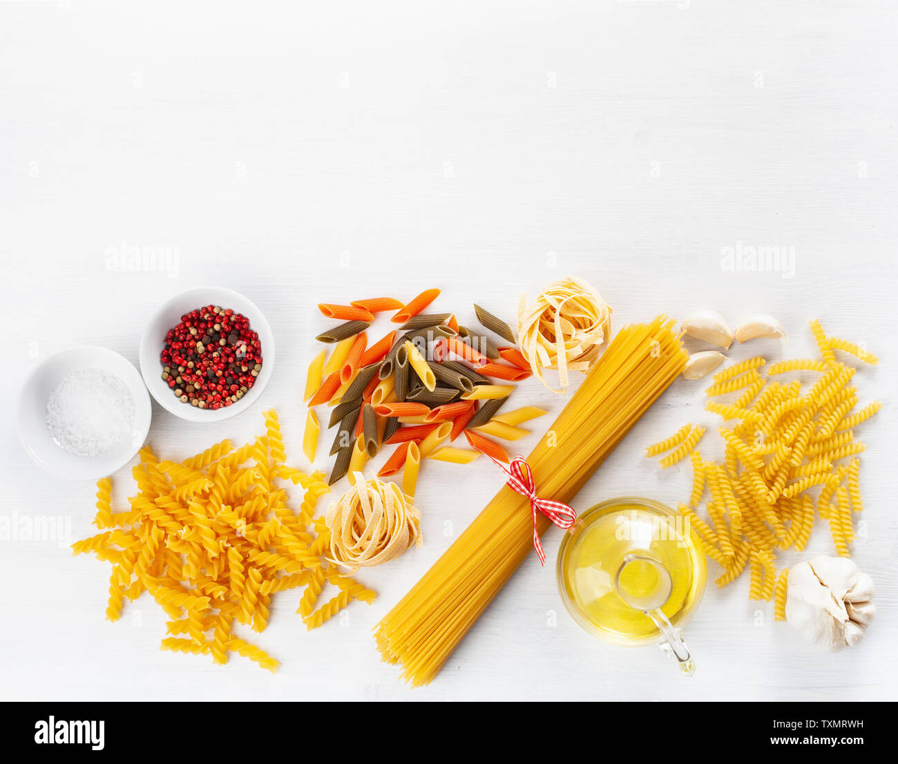 Un assortimento di pasta cruda laici piatta sul bianco. spaghetti fusilli penne tagliatelle girandole Foto Stock