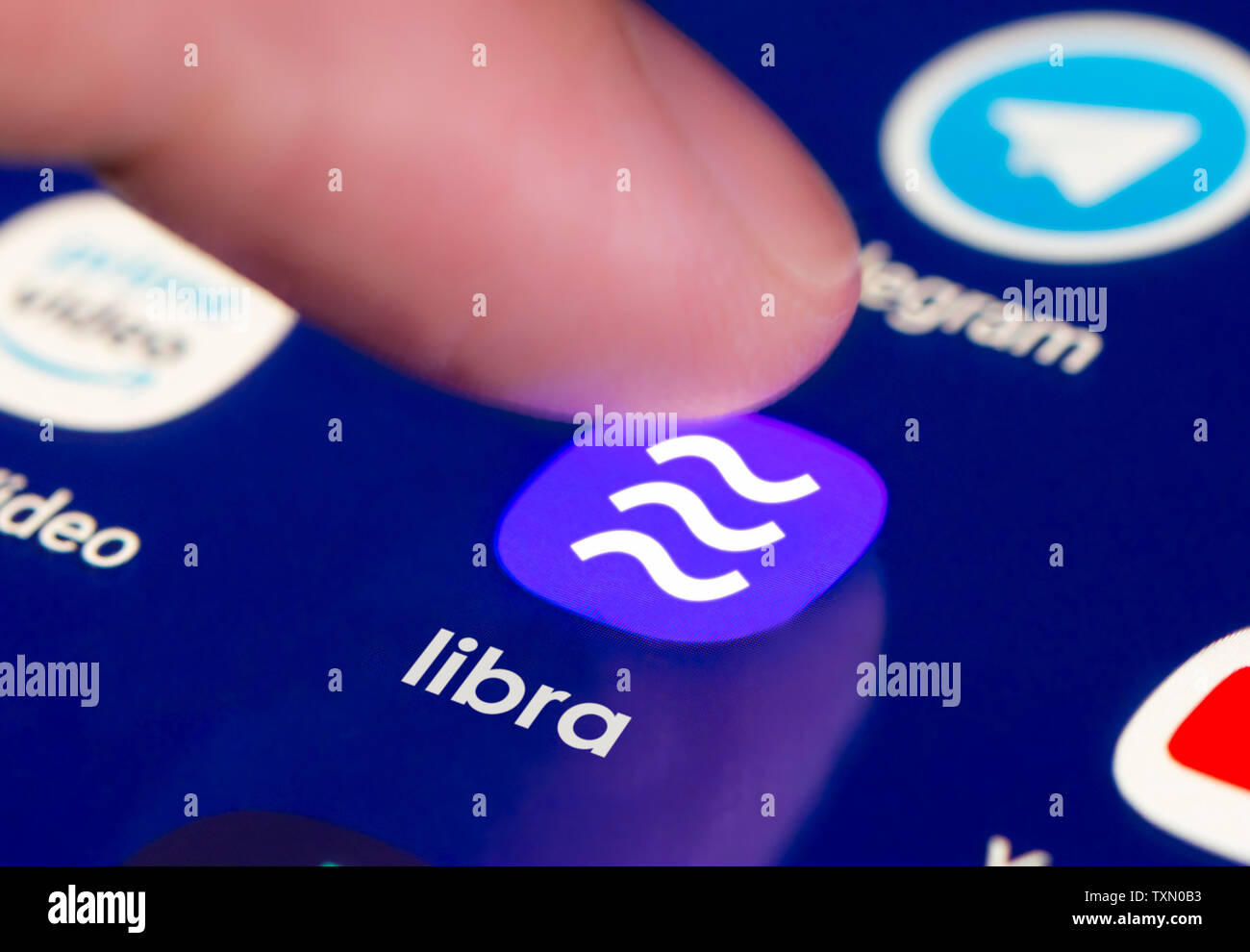 Dito premendo il pulsante sul touchscreen per caricare Libra app per uso di Facebook di Libra cryptocurrency blockchain technology service. Foto Stock