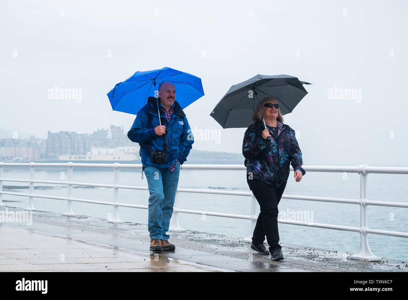 Aberystwyth Wales UK, martedì 25 giugno 2019 UK Meteo: gente camminare sul lungomare di Aberystwyth, avvolto fino contro la pioggia e ombrelli azienda contro la pioggia su una noiosa umido e nuvoloso pomeriggio . Le condizioni di Ares impostato a modificare radicalmente il weekend con un pennacchio di caldo e soleggiato fino dal continente, portare ing temperature nella metà degli anni venti gradi centigradi Photo credit: keith morris/Alamy Live News Foto Stock