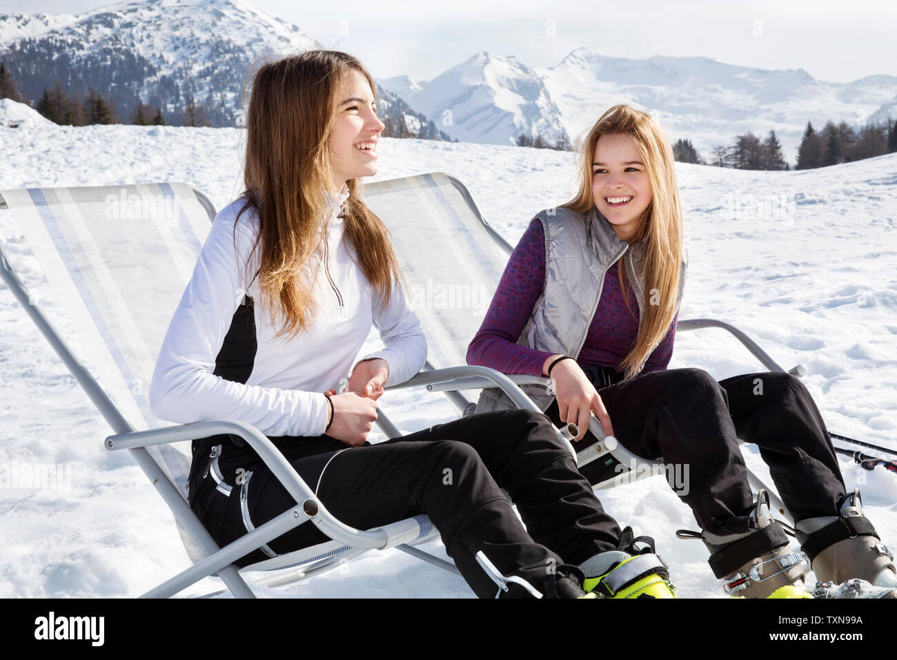 Due teenager sciatori seduti in sedie a sdraio in paesaggi innevati, Tirolo, Stiria, Austria Foto Stock