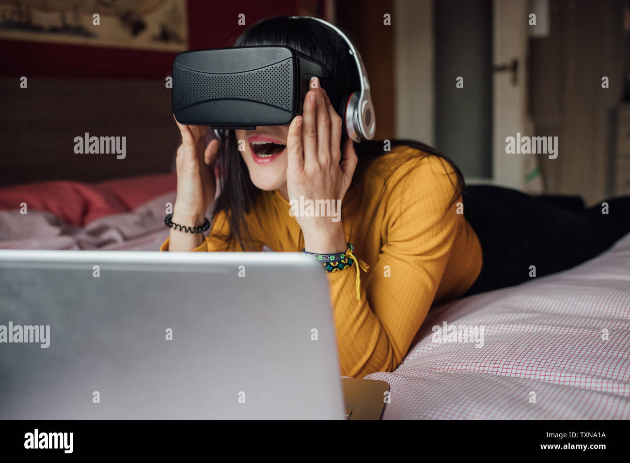 Donna con cuffie VR sul letto Foto Stock