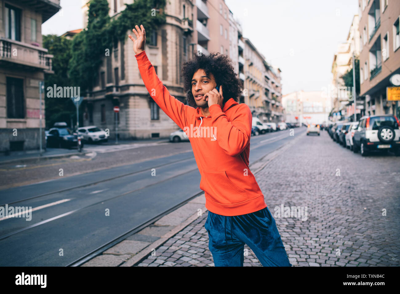 Giovane uomo salutando cabina in città, Milano, Lombardia, Italia Foto Stock