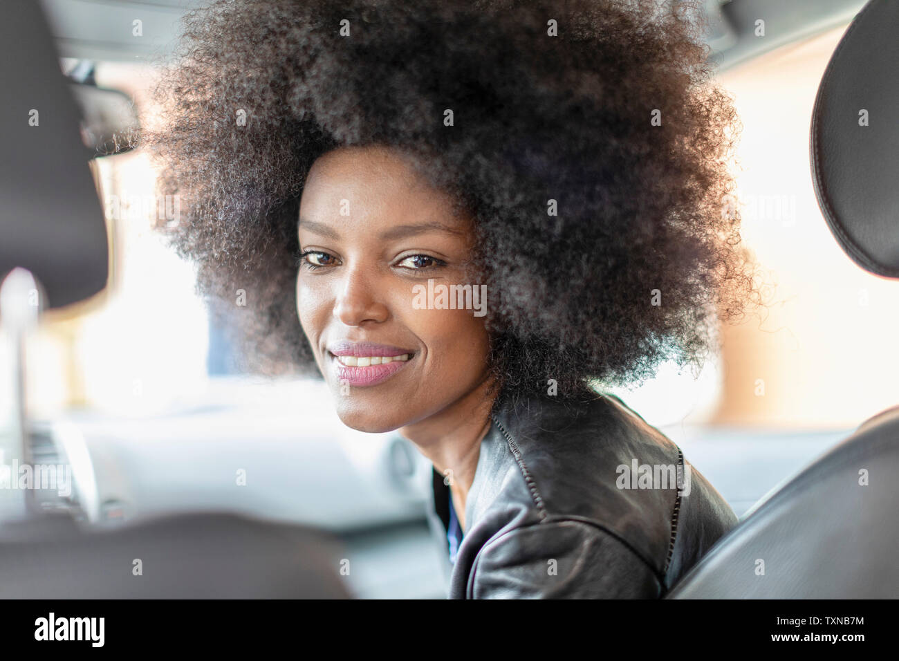 Felice giovane donna con capelli afro in auto sedile passeggero, ritratto Foto Stock