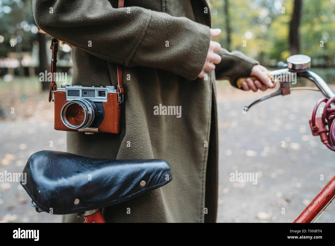 Giovane donna con telecamera e bicicletta in autunno park, metà sezione Foto Stock