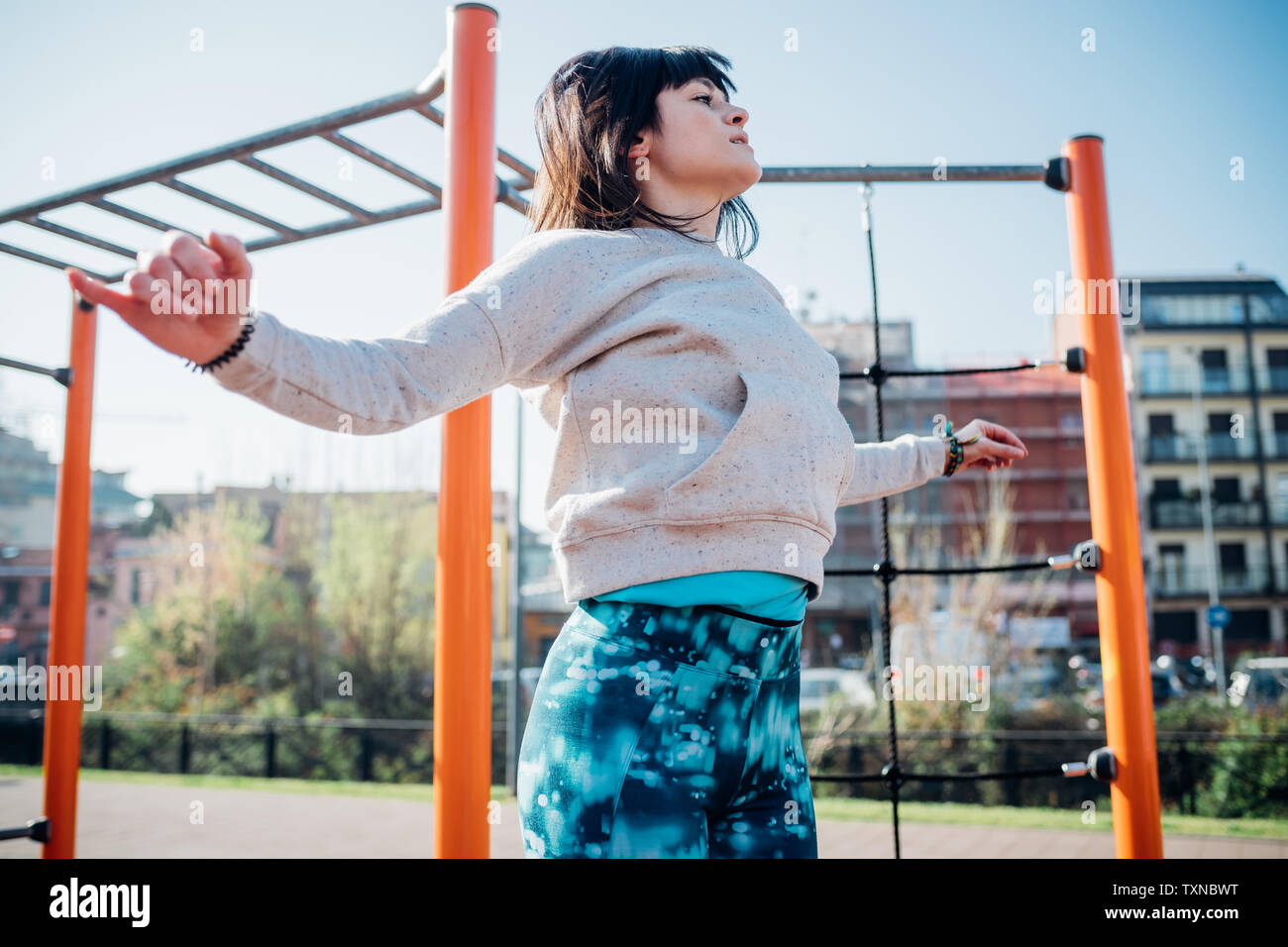 Classe Calisthenics presso palestra all'aperto, giovane donna salta con le braccia aperte Foto Stock