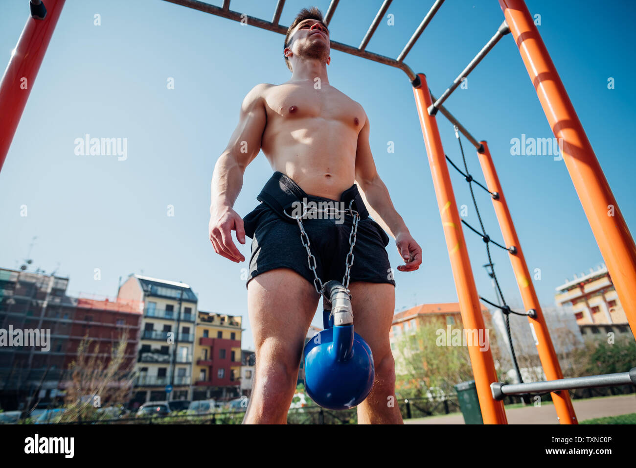 Calisthenics presso palestra all'aperto, bare chested giovane uomo in piedi  con kettlebell sulla cintura a vita Foto stock - Alamy
