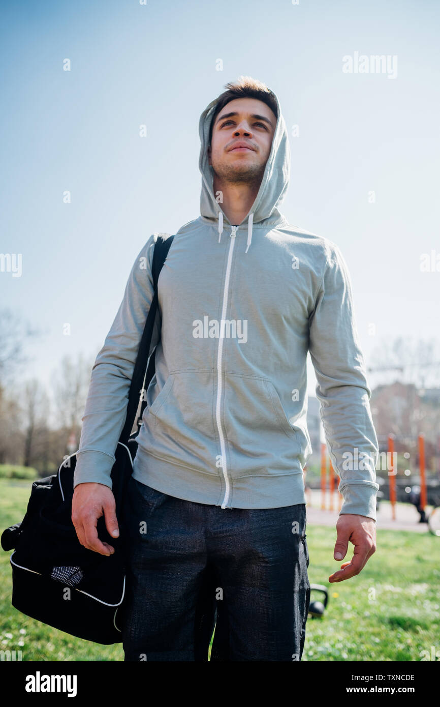 Calisthenics presso palestra all'aperto, giovane uomo che porta borsa sportiva Foto Stock