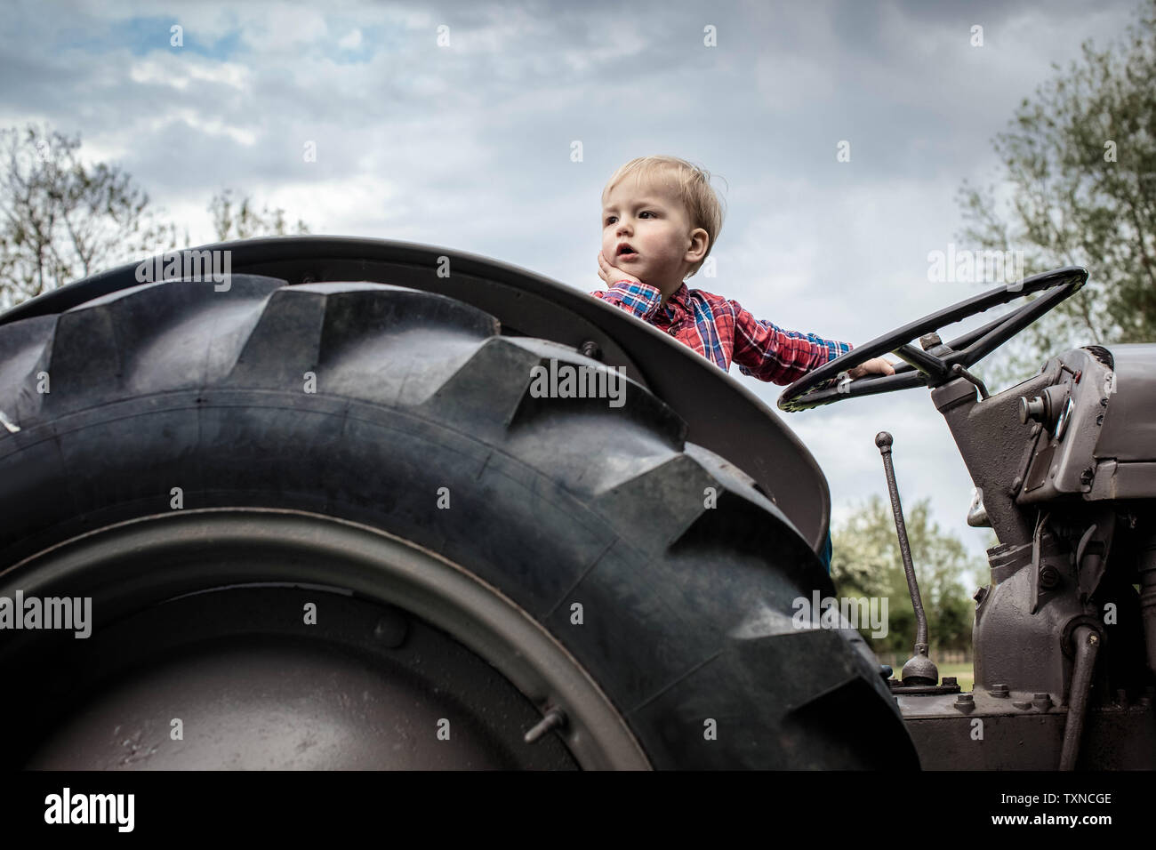 Il Toddler nel pensiero profondo sul trattore Foto Stock