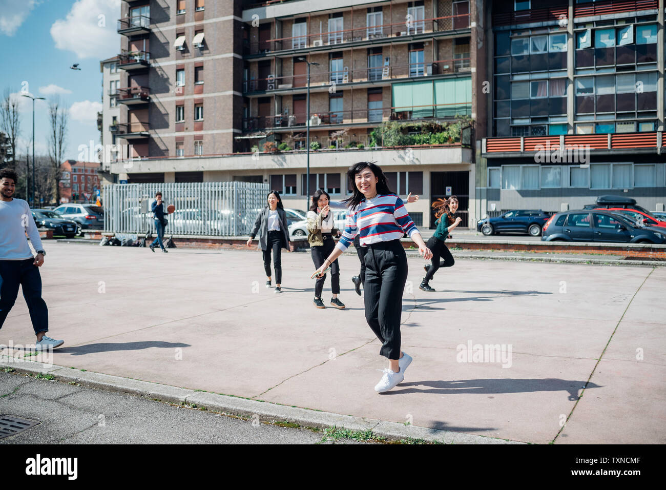 I giovani di sesso maschile e femminile amici adulti ingannare intorno sulla città di basket Foto Stock