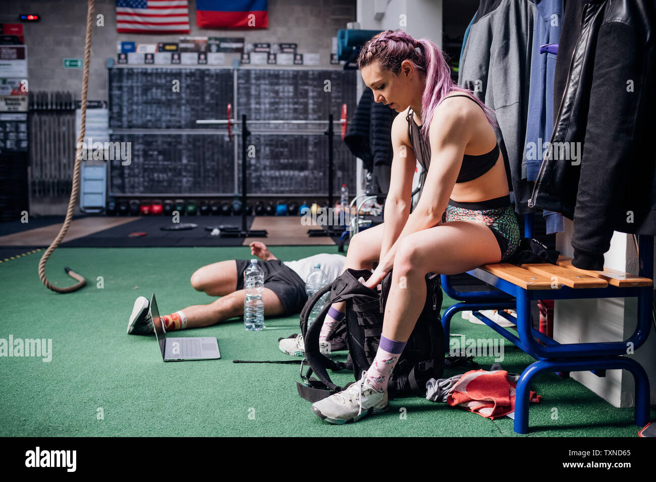 Giovane donna formazione, seduti su una panchina di imballaggio borsa sportiva in palestra Foto Stock