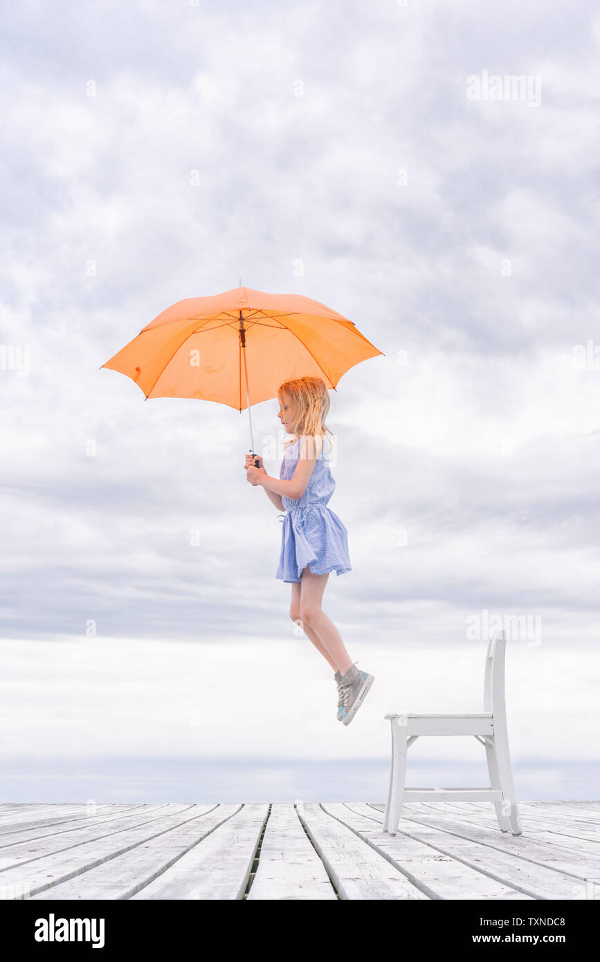 La ragazza che viene sollevato fuori la sua sedia di ombrello Foto Stock