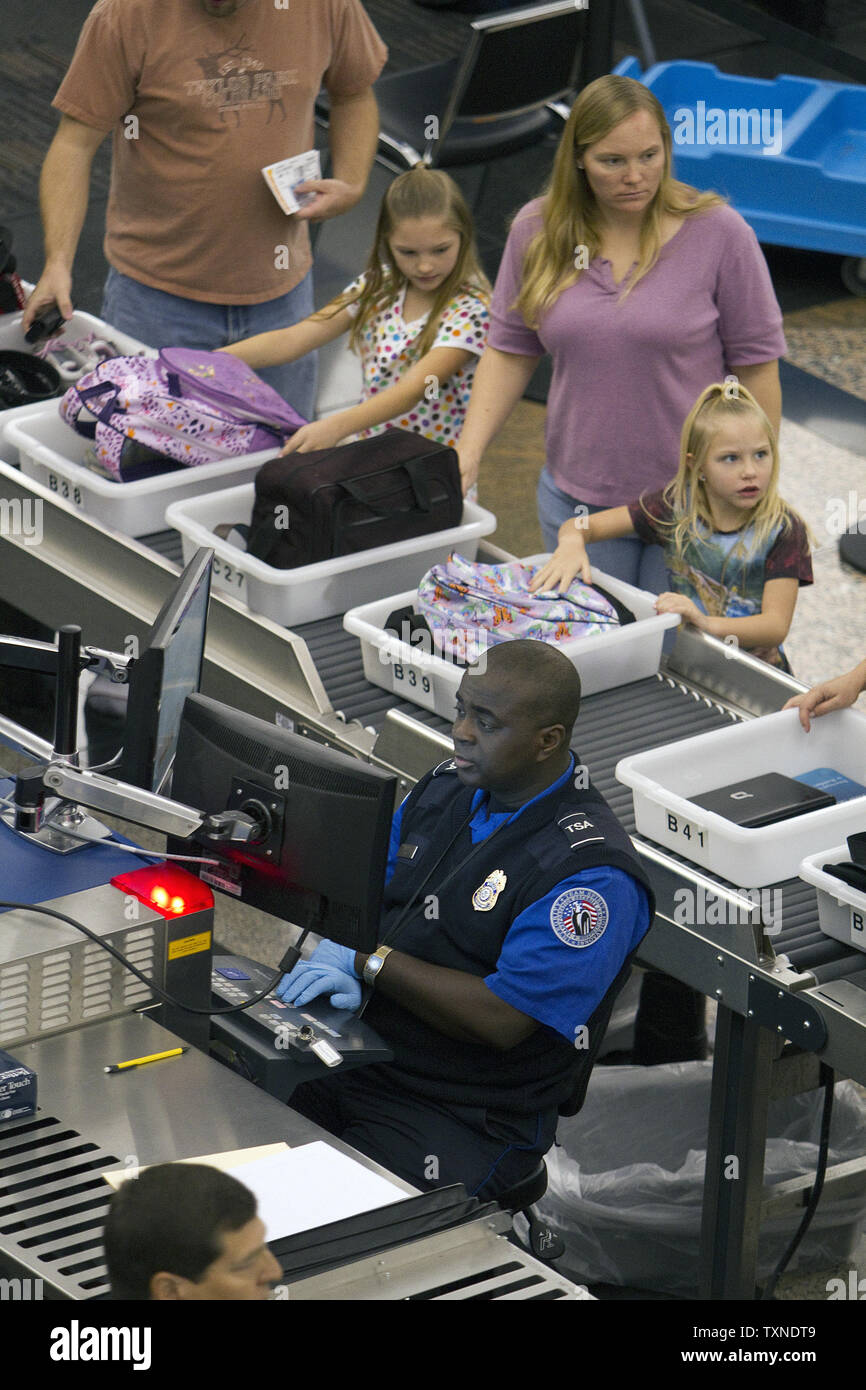 Un Transportation Security Administration (TSA) Agent esegue una scansione mentre i bambini attendere il loro turno per passare attraverso il sistema di sicurezza all'Aeroporto Internazionale di Denver di meno di una settimana di distanza dalla festa del Ringraziamento a Novembre 19, 2010 a Denver. I bambini al di sotto dei dodici anni di età possono essere esentati per il nuovo pat aggressivo verso il basso le tecniche di ricerca impiegati dal TSA. UPI/Gary Caskey C. Foto Stock