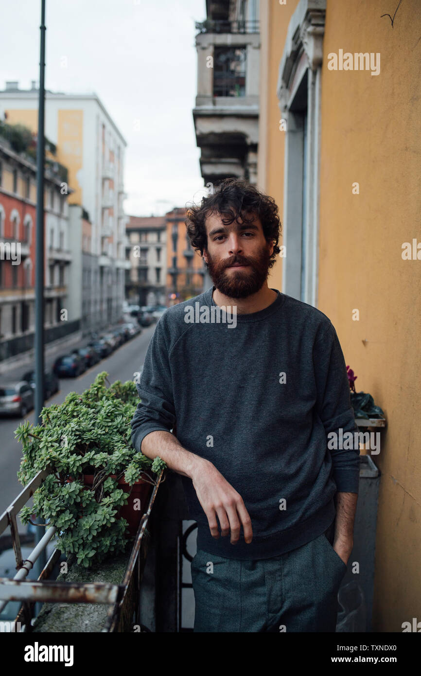 Barbuto giovane nel pensiero profondo sul balcone Foto Stock