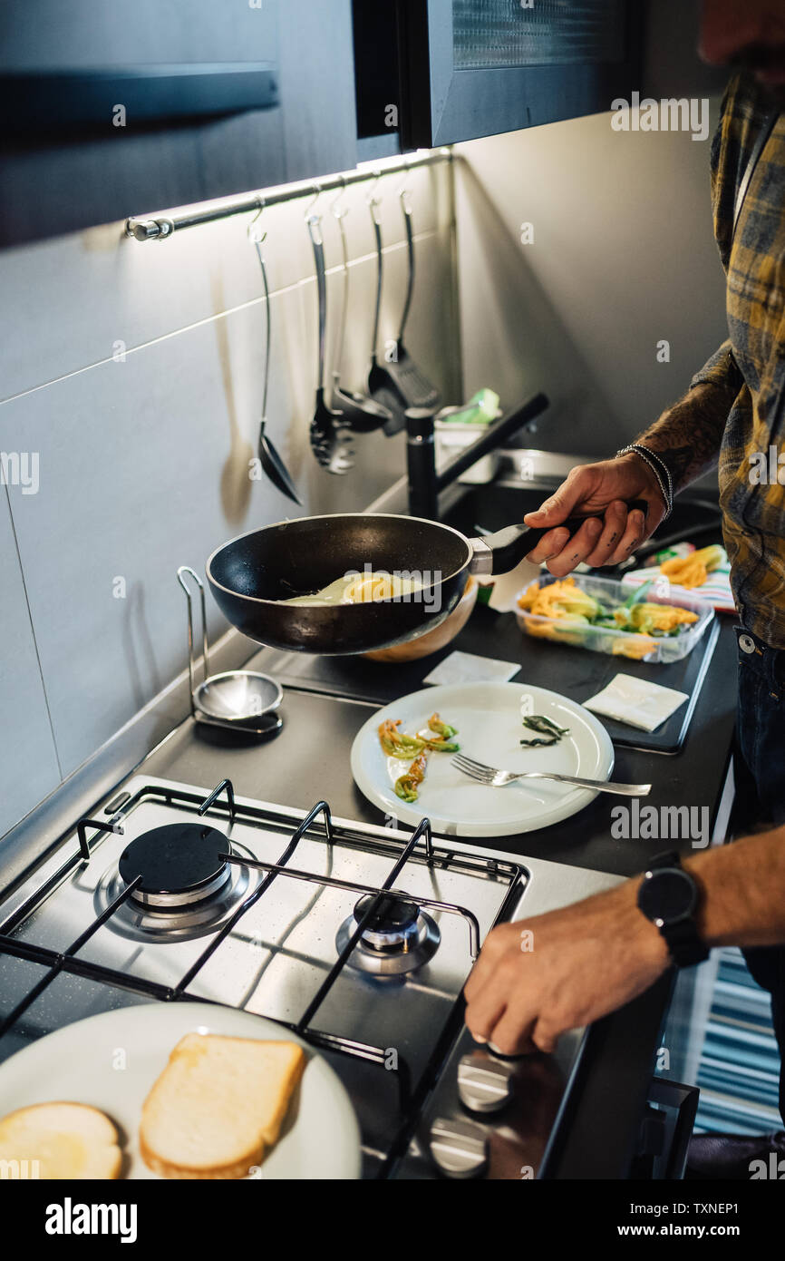Metà uomo adulto preparare uova fritte al piano di cottura per cucina, ritagliato Foto Stock