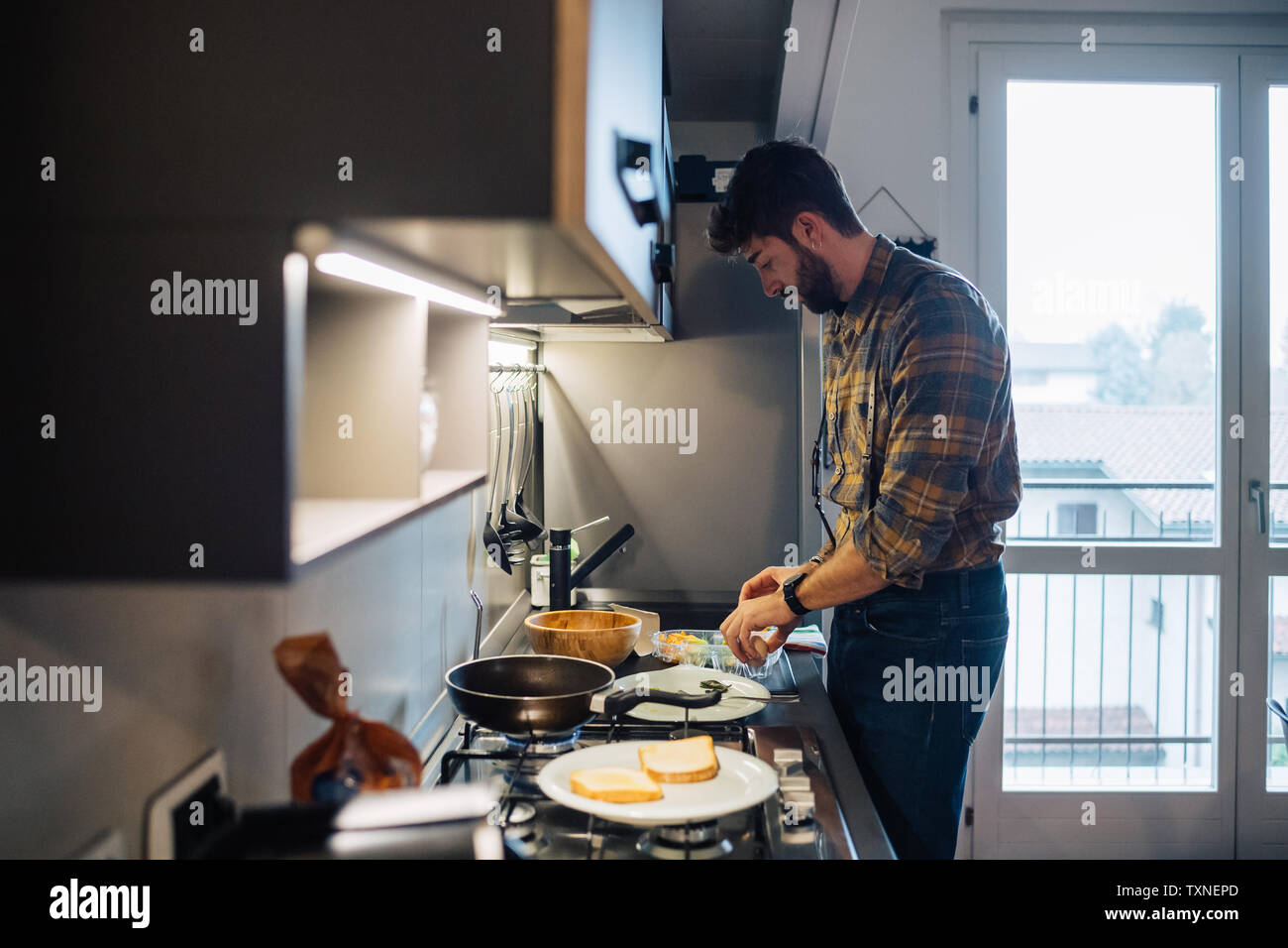 Metà uomo adulto preparare il cibo al piano di cottura per cucina Foto Stock