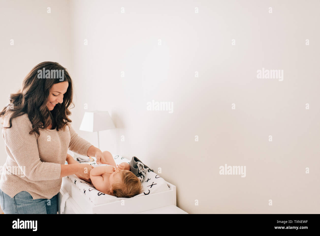 Madre modifica baby figlia di pannolino in vivaio Foto Stock
