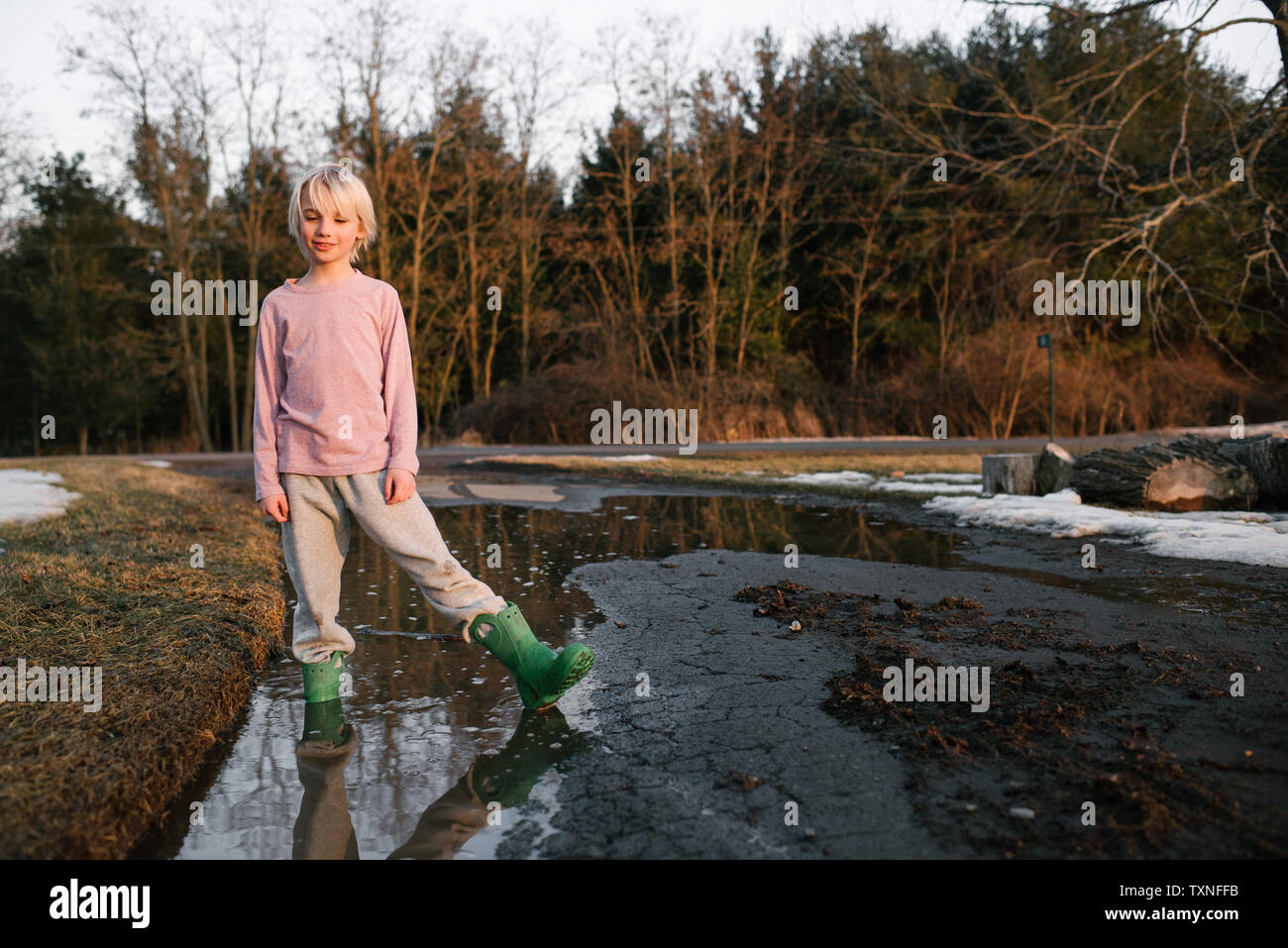 Ragazzo in piedi profondo della caviglia in acqua di disgelo rurale pozza, ritratto Foto Stock