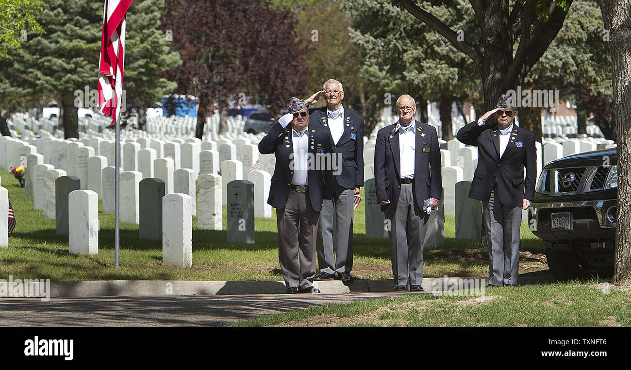Veterani salutate come rubinetti viene riprodotto durante una U.S. Navy funerale avviene dopo i volontari posto bandierine americane a gravesites in preparazione per il Memorial Day a Fort Logan Cimitero Nazionale a Denver il 28 maggio 2011. Il Memorial Day celebrato il 30 maggio onori tutti quei servizi armati di uomini e donne che sono morti nel servizio militare per gli Stati Uniti. UPI/Gary Caskey C. Foto Stock