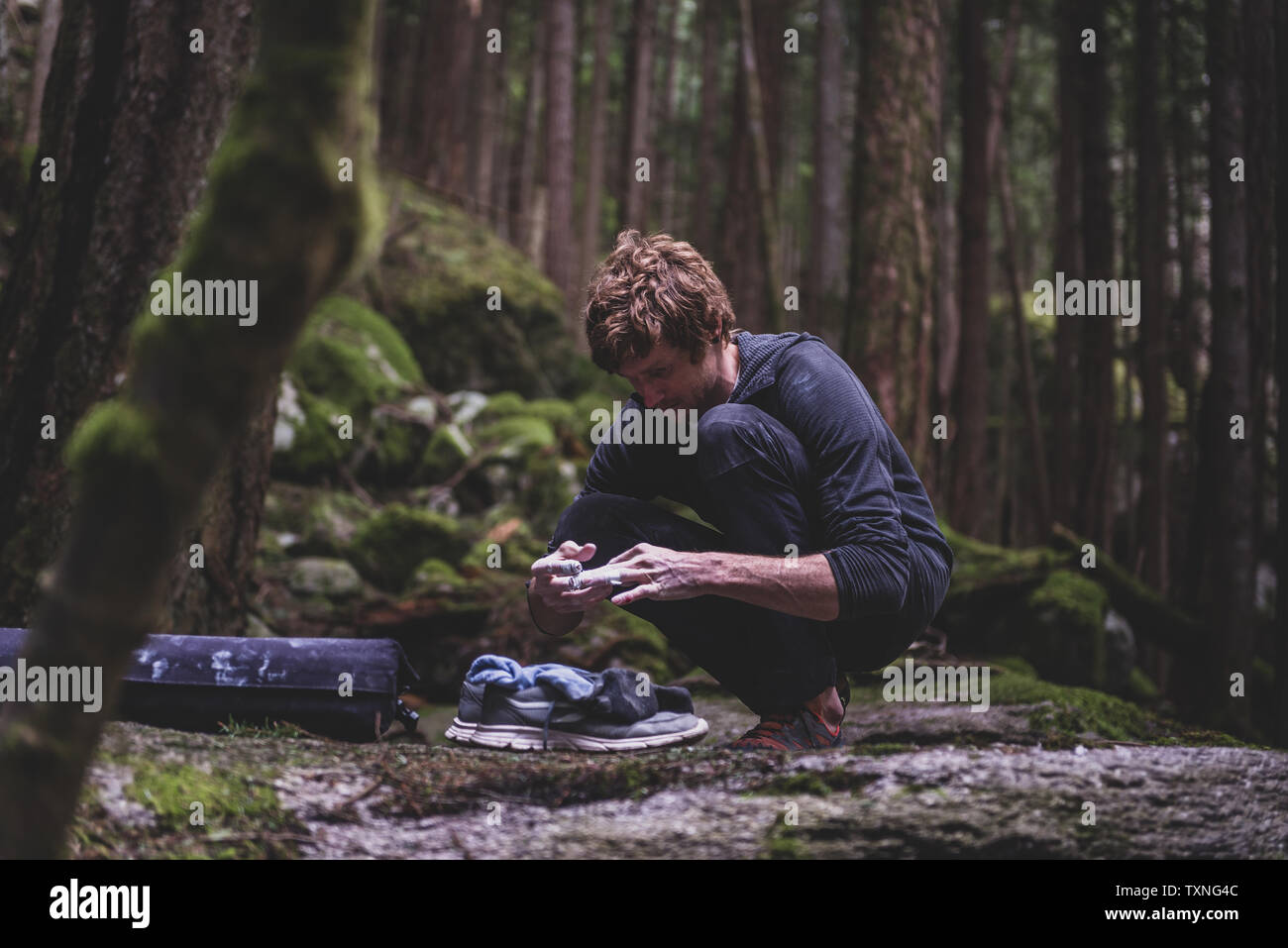 Scalatore la nastratura dita prima di bouldering in foresta, Squamish, Canada Foto Stock