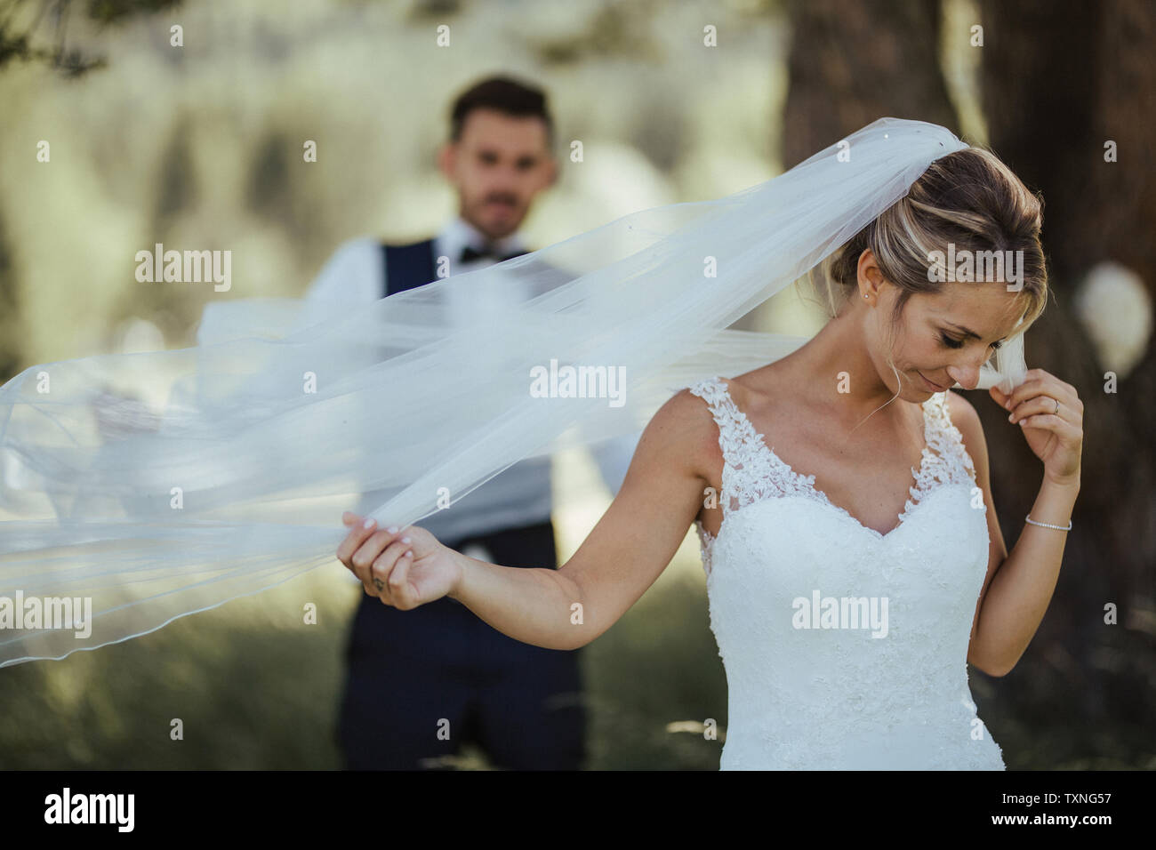 Sposa e lo sposo holding delicato velo nuziale nel bosco Foto Stock