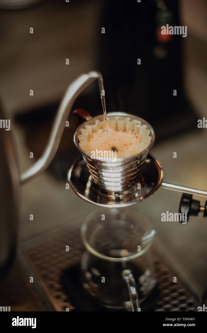 Bollito di Bollitore acqua versando in un filtro del caffè sul contatore cafe, close up shallow focus Foto Stock