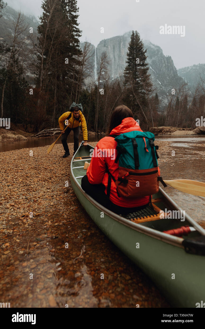 Canoa giovani giovane spingendo fuori dal riverbank, il Villaggio di Yosemite in California, Stati Uniti d'America Foto Stock