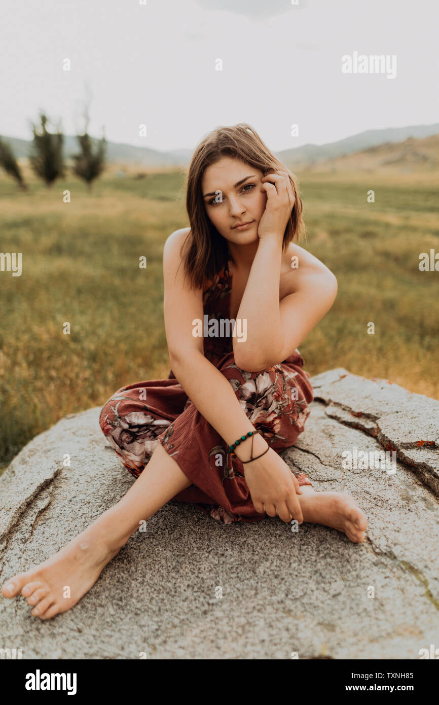 Bella giovane donna seduta zampe trasversale sul boulder, ritratto, Exeter, CALIFORNIA, STATI UNITI D'AMERICA Foto Stock