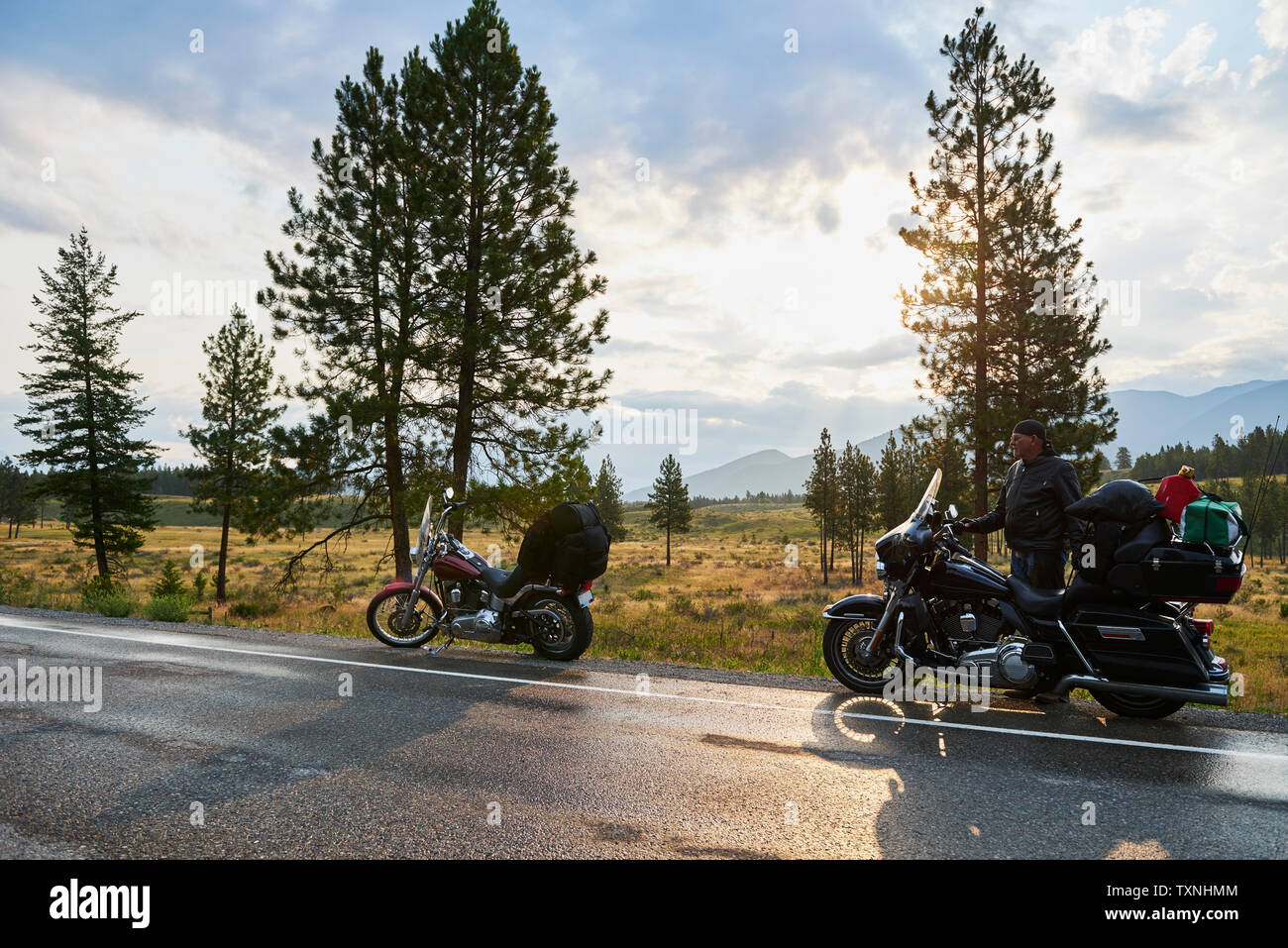 Senior motociclista maschio sulla strada rurale con moto, Dawson Creek, Canada Foto Stock