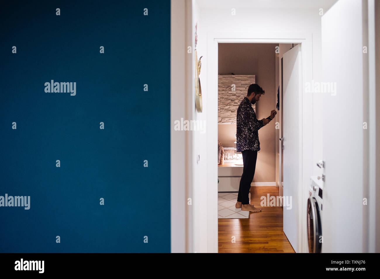 Metà uomo adulto di vestirsi in camera da letto, vista dal corridoio Foto Stock