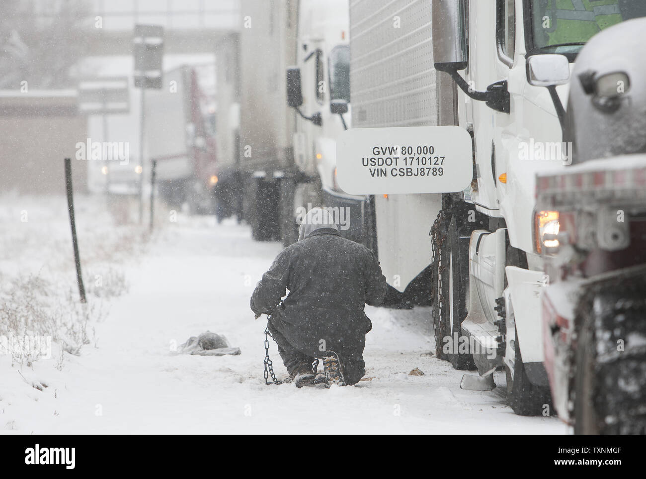 Un camionista mette sulla sua catene da neve sulla Interstate 70 durante una tempesta di neve di colpire di Denver e voce per la pianura orientale il 4 dicembre 2013. UPI/Gary Caskey C. Foto Stock