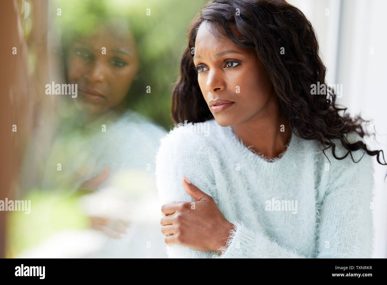 Donna etnica cercando triste sat in una finestra Foto Stock