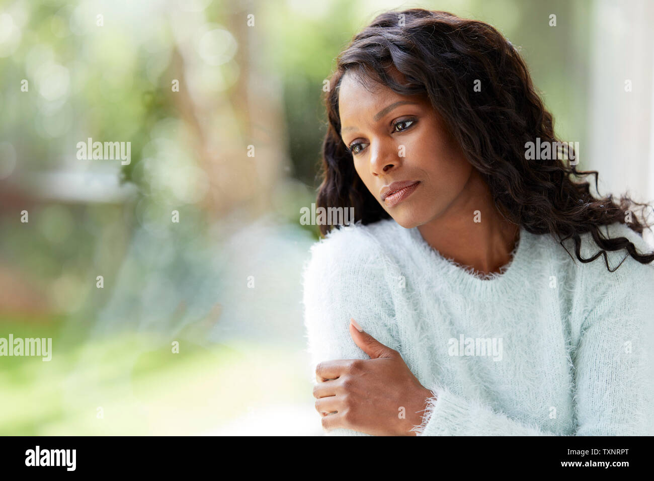 Donna etnica cercando triste sat in una finestra Foto Stock
