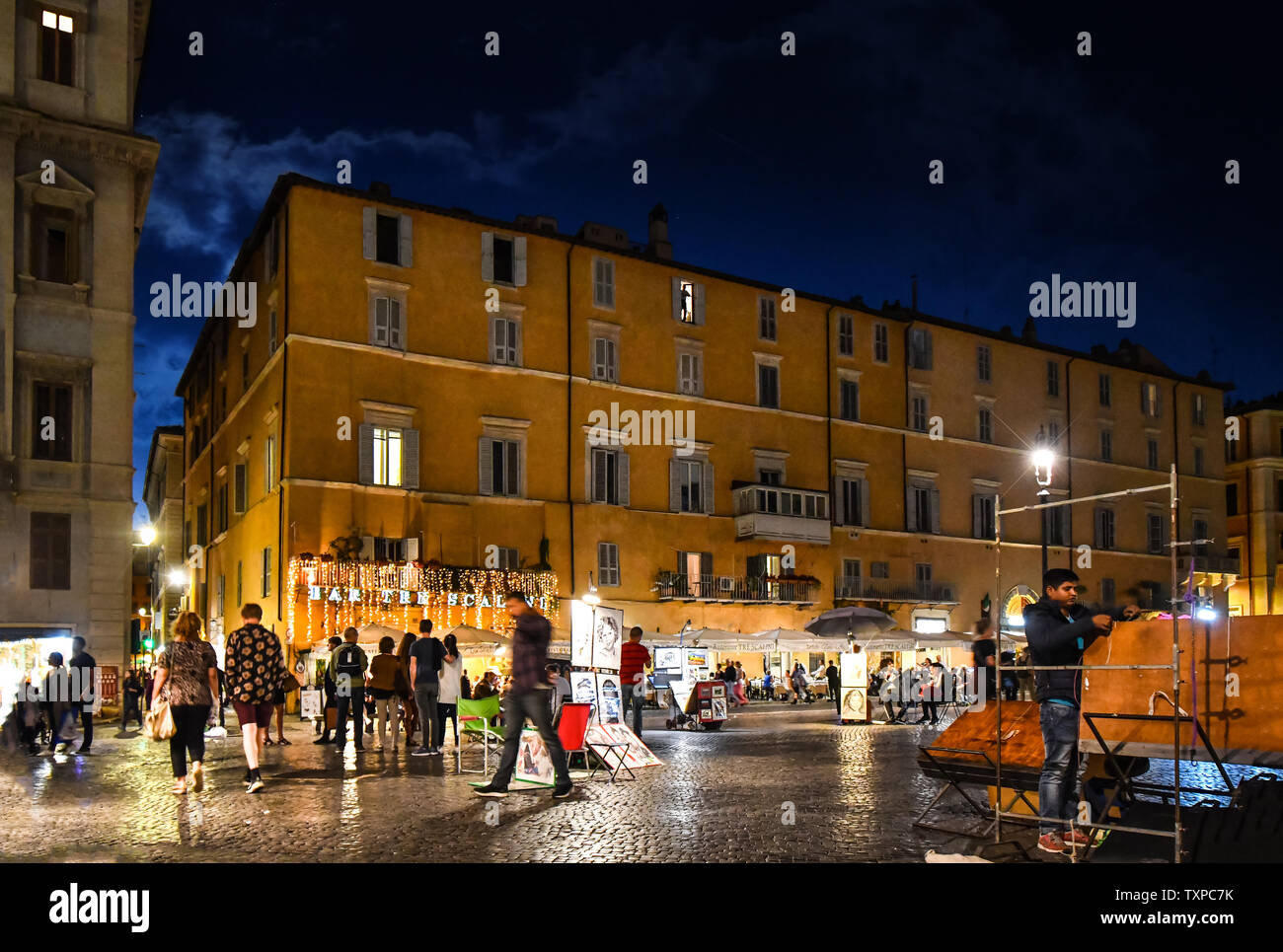 A tarda notte sulla Piazza Navona come turisti e artisti di strada si mescolano in da negozi e caffetterie in Roma, Italia. Foto Stock