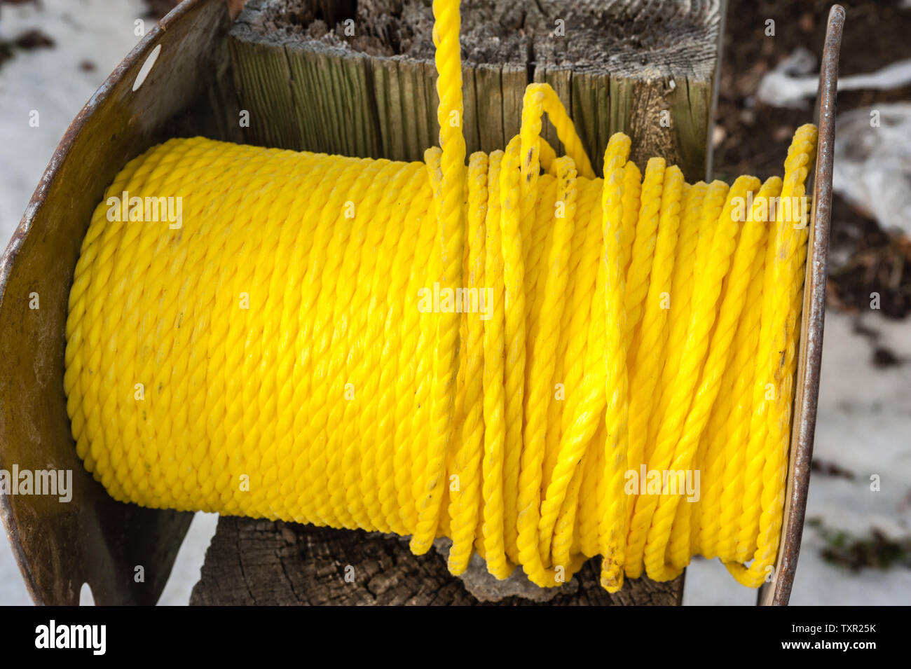 Rocchetto di plastica avvolto corda giallo sul palo di legno. Foto Stock
