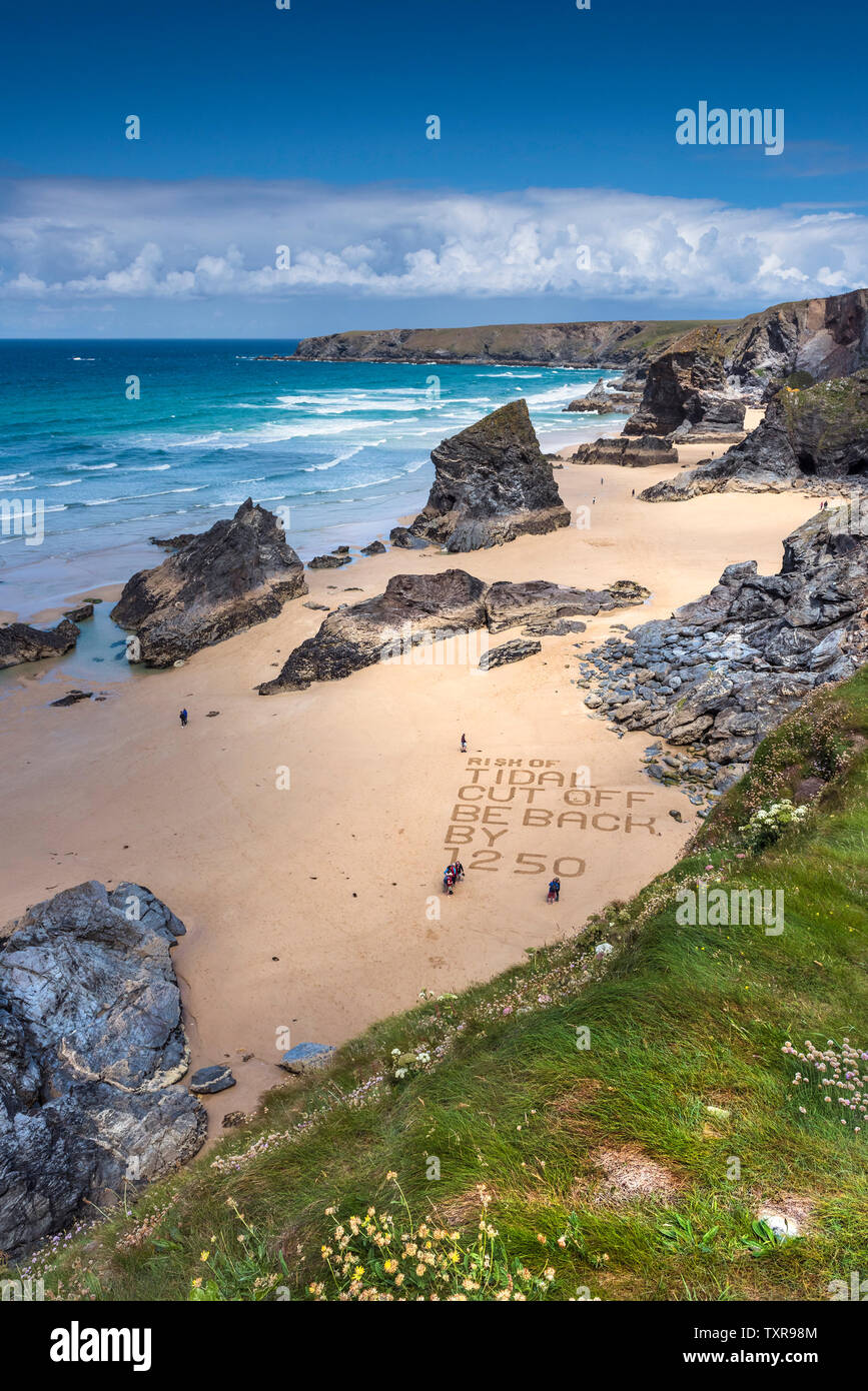 Un messaggio di avvertimento scritto nella sabbia sulla spiaggia di robusta e spettacolare Bedruthan Steps sulla North Cornwall Coast. Foto Stock