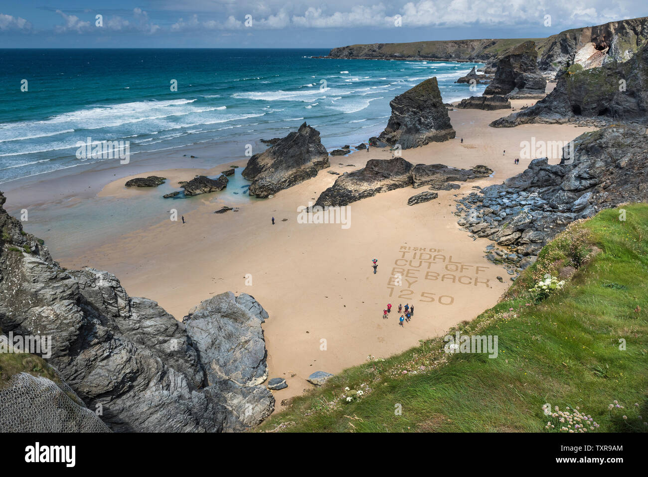 Un messaggio di avvertimento scritto nella sabbia sulla spiaggia di robusta e spettacolare Bedruthan Steps sulla North Cornwall Coast. Foto Stock