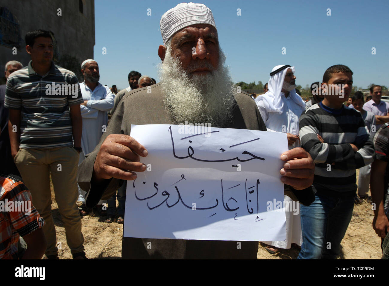 Un uomo palestinese tenere cartello con le parole arabe "Ci torneremo sicuramente a Haifa' durante un rally segnando il sessantasettesimo anniversario della "La Nakba" il 15 maggio 2015 vicino al confine con Israele, a est di Khan Younis nel sud della striscia di Gaza. 'La Nakba" significa in arabo "catastrofe" in riferimento alla nascita dello Stato di Israele 67 anni fa in British-Palestina mandataria, che ha causato lo sfollamento di centinaia di migliaia di palestinesi che sono fuggiti o sono stati cacciati dalle loro case durante la guerra del 1948 su Israele per la creazione. Foto di Ismael Mohamad/UPI Foto Stock