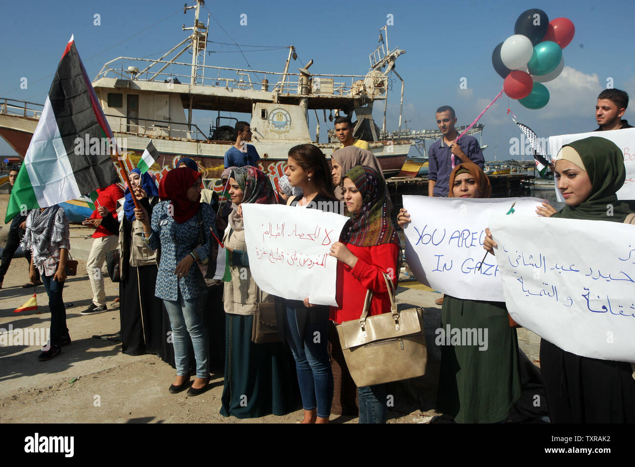 Palestinesi solidarietà con una striscia di Gaza-bound flottiglia di attivisti internazionali di tentare di rompere il blocco israeliano sulla striscia di Gaza, il 5 ottobre 2016, presso il porto di Gaza City. Un gruppo di donne cercano di raggiungere la striscia di Gaza a bordo di una imbarcazione (Zaytouneh barca) nel tentativo di rompere un decennio-lungo il blocco da parte di Israele, un portavoce ha detto. La flottiglia soprannominato "Donne della barca alla striscia di Gaza", fa parte della più ampia libertà flottiglia coalizione che consiste di pro-palestinese barche che regolarmente vanno a Gaza da tutto il mondo per provare a rompere il blocco. Foto di Ismael Mohamad/UPI. Foto Stock