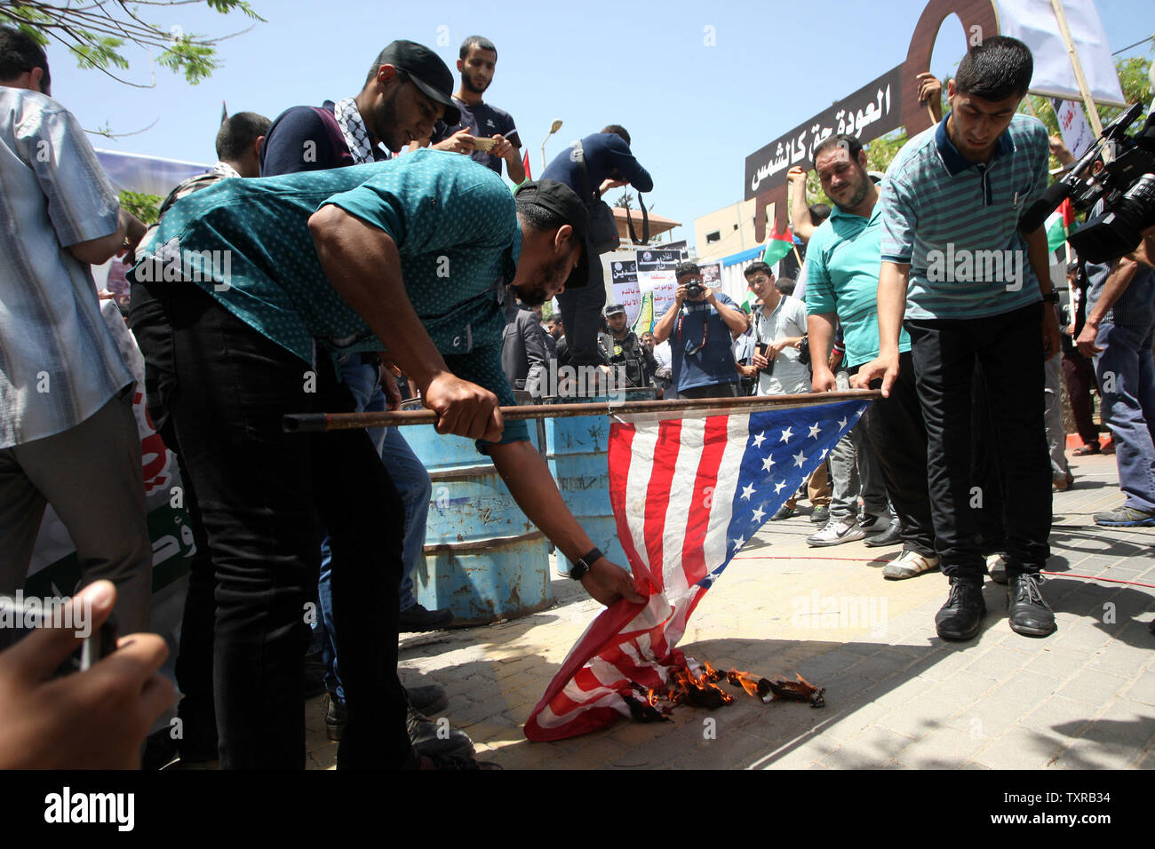 Dimostranti palestinesi bruciare una bandiera americana durante un rally per contrassegnare la sessantanovesima anniversario della 'La Nakba','arabo "catastrofe", il termine utilizzato per contrassegnare gli eventi che portano a Israele la fondazione nel 1948, nella città di Gaza, il 15 maggio 2017. 'La Nakba" significa in arabo "catastrofe" in riferimento alla nascita dello Stato di Israele 69 anni fa in British-Palestina mandataria, che ha causato lo sfollamento di centinaia di migliaia di palestinesi che sono fuggiti o sono stati cacciati dalle loro case durante la guerra del 1948 su Israele per la creazione. La chiave simboleggia le case a sinistra dai palestinesi nel 1948, più di 76 Foto Stock