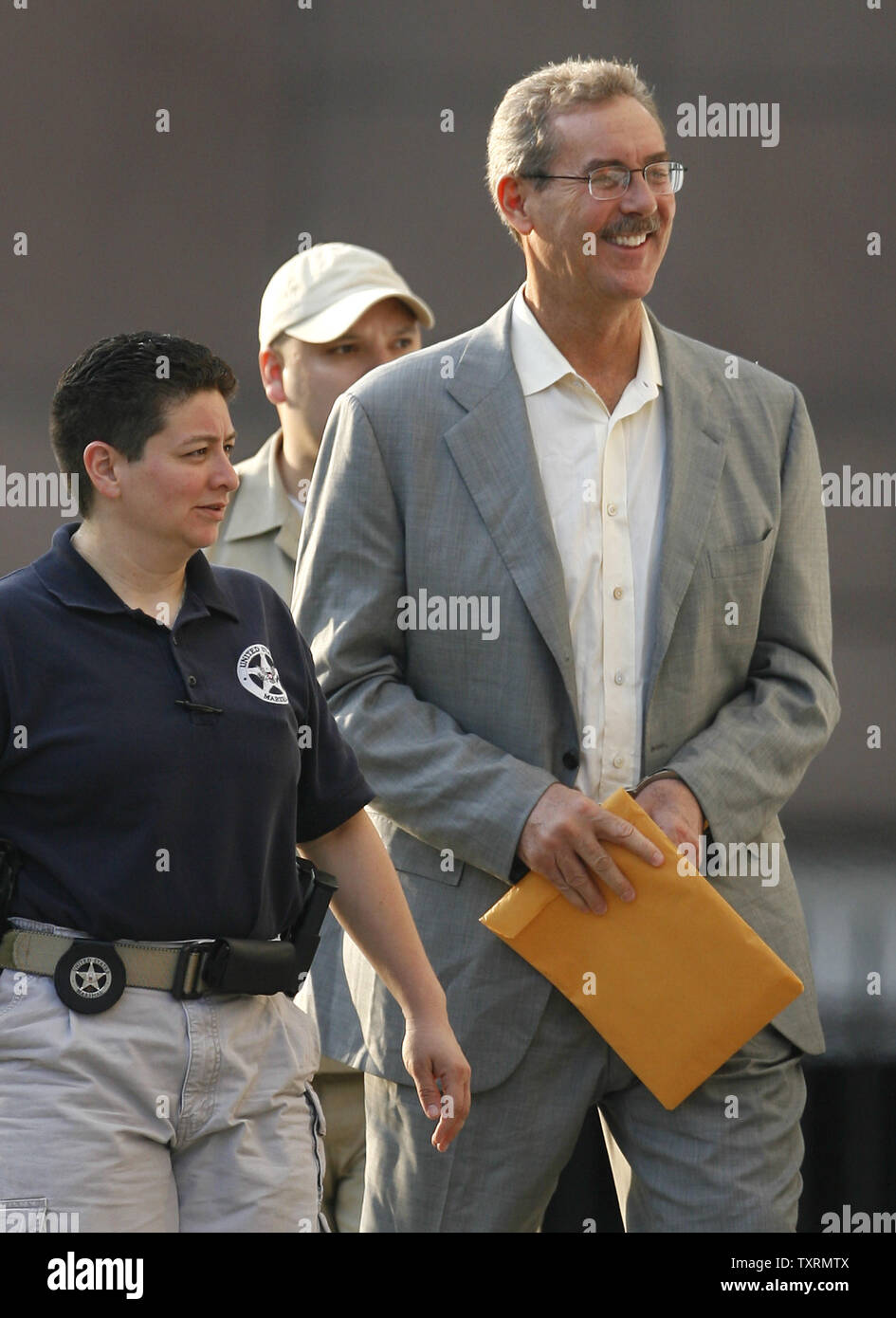 Finanziere R. Allen Stanford (R) è scortato in Federal Courthouse in manette per un' audizione su se un ordine concessione lui bail dovrebbe essere invertita a Houston, in Texas, il 29 giugno 2009. Stanford è stato incriminato da un gran giurì federale insieme ad altre cinque persone tra cui un ex regolatore Antiguan su oneri hanno diretto a 7 miliardi di dollari di frode per la vendita di certificati di deposito attraverso la sua banca Antiguan. (UPI foto/Aaron M. Sprecher) Foto Stock